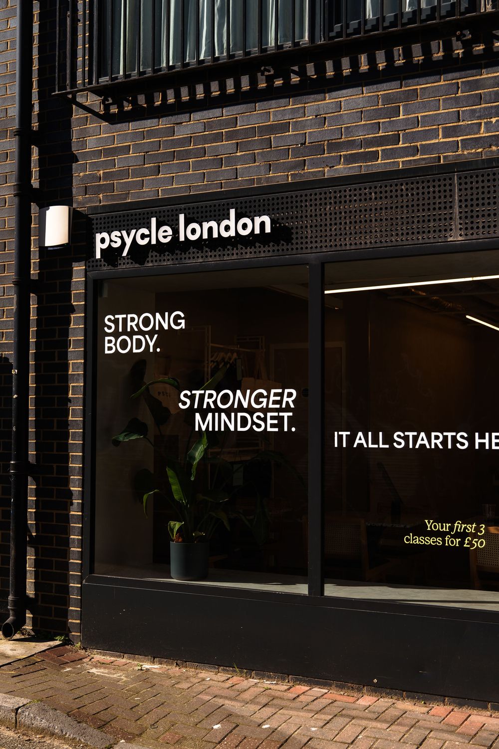 Psycle London fitness studio storefront with motivational text Strong Body Stronger Mindset on dark window display.