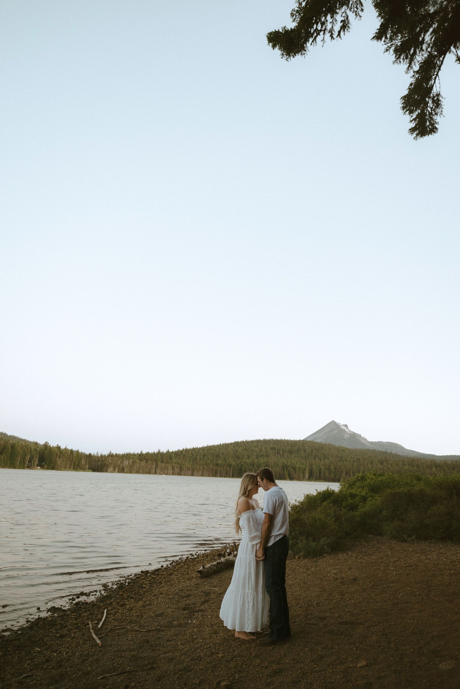 A couple shares a romantic moment in front of a modern glass office building in black and white photography.