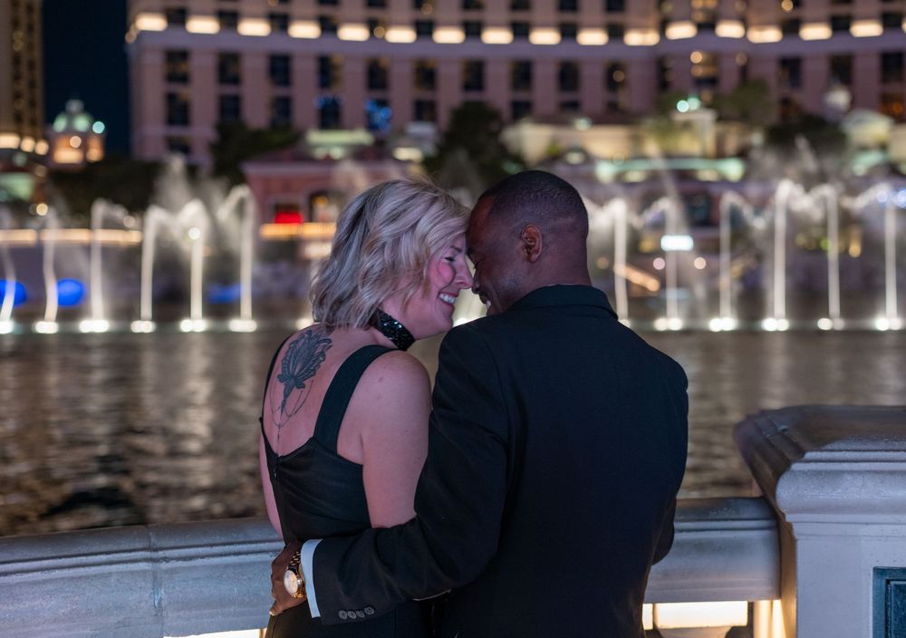 Couple embracing while watching the illuminated Bellagio fountains at night in Las Vegas.