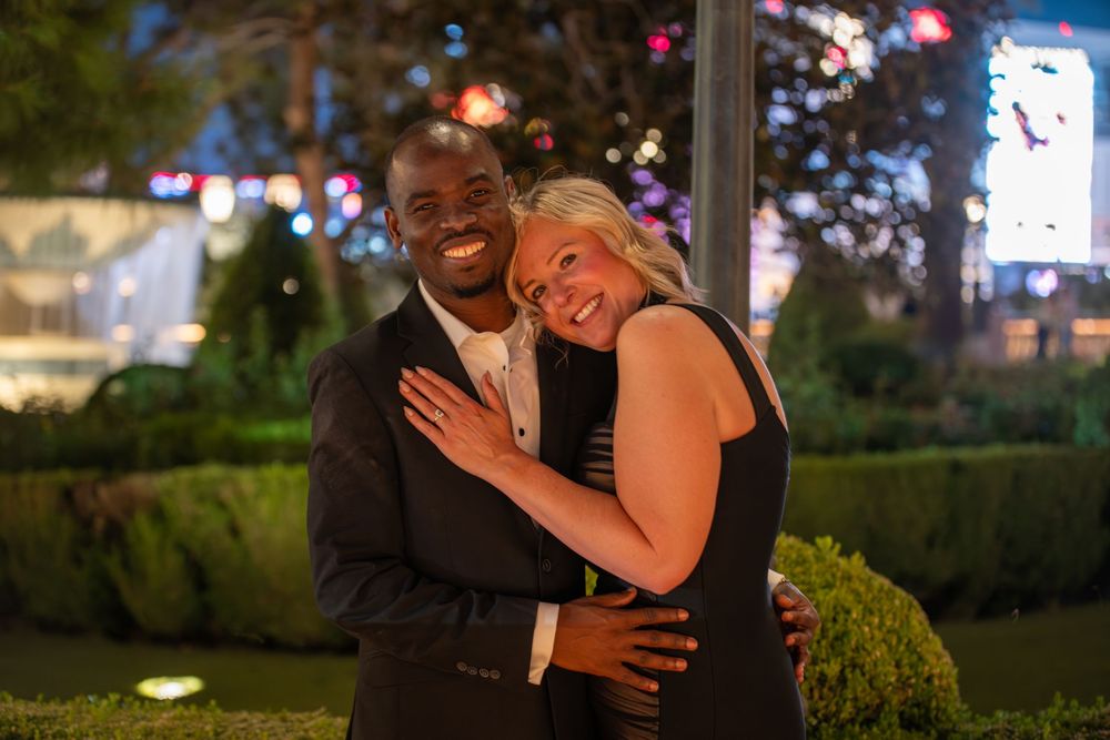 Happy couple embracing and smiling outdoors on the Las Vegas Strip at night.