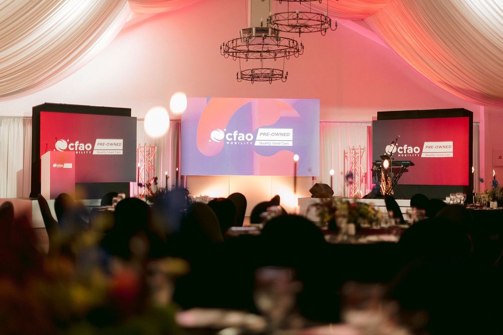 CFAO corporate gala dinner event with elegant stage setup, draped ceilings, and branded screens in a decorated banquet hall.