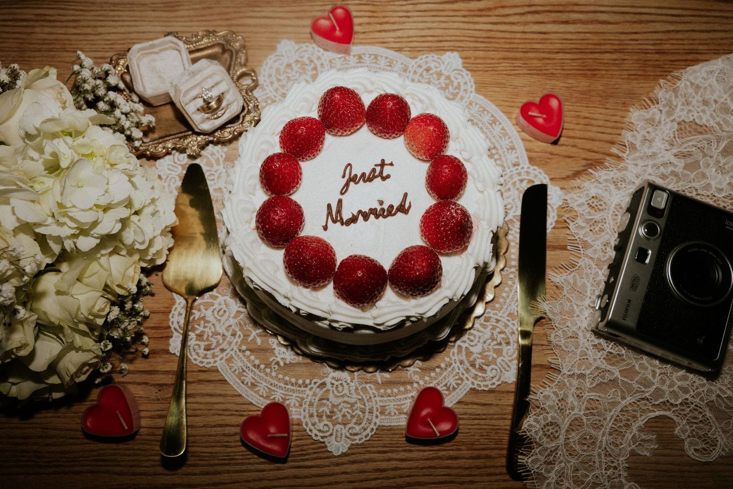 Wedding decorations featuring red hearts and lace doilies on a rustic wooden table.