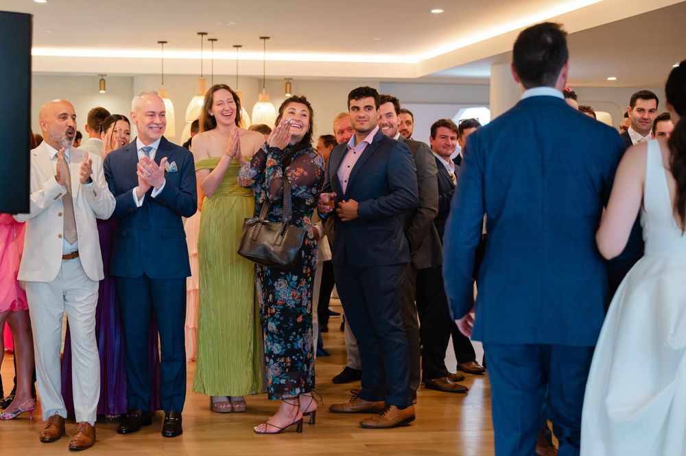 Wedding reception guests take photos at the edge of a dance floor during a formal celebration.
