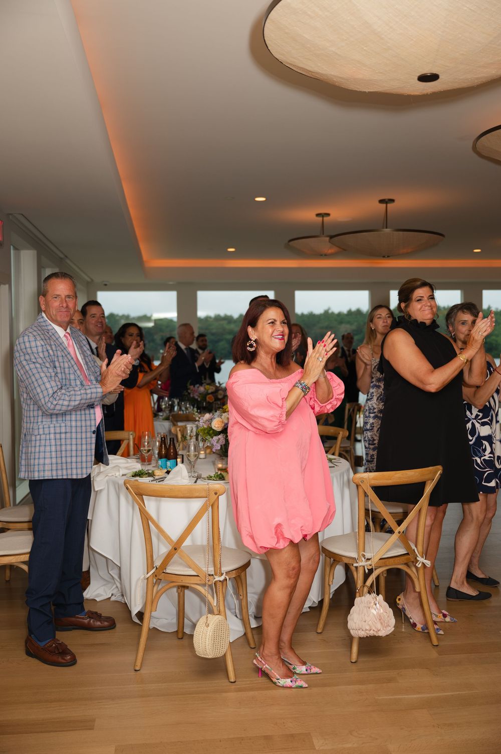People dance together on the wooden floor during a celebration party in an elegant venue with soft lighting.