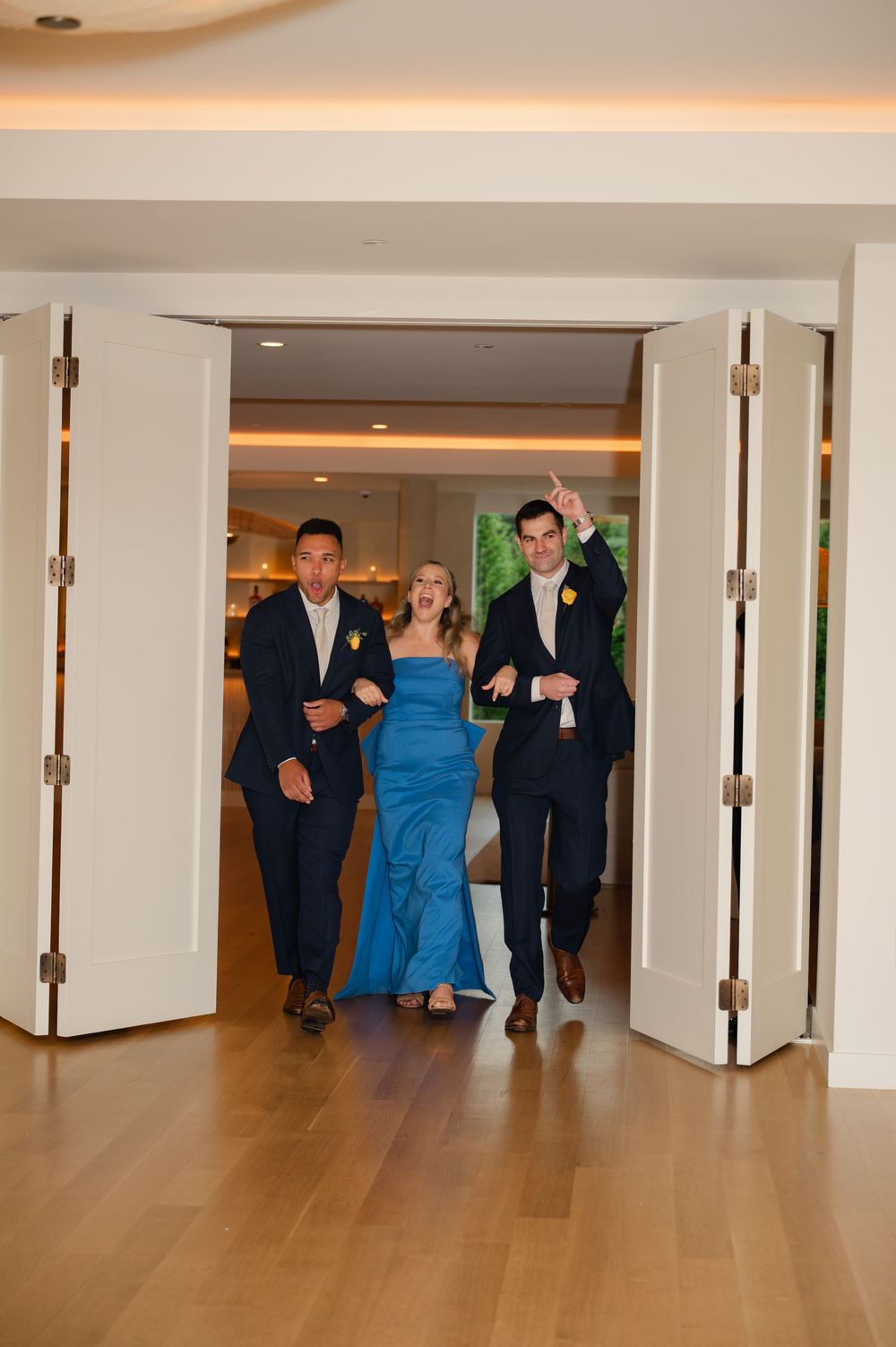 A series of images showing people walking down a hallway in formal attire with recessed lighting and wood flooring.