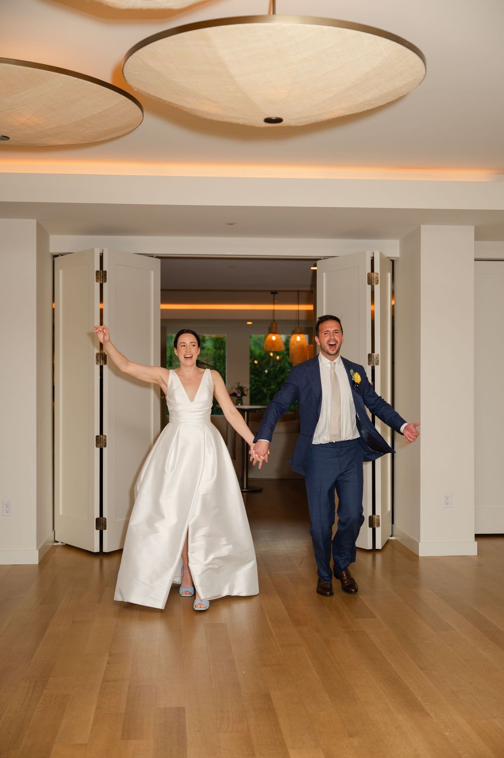 A sequence of photos showing a couple in wedding attire dancing and posing playfully in a modern empty room with wood floors.