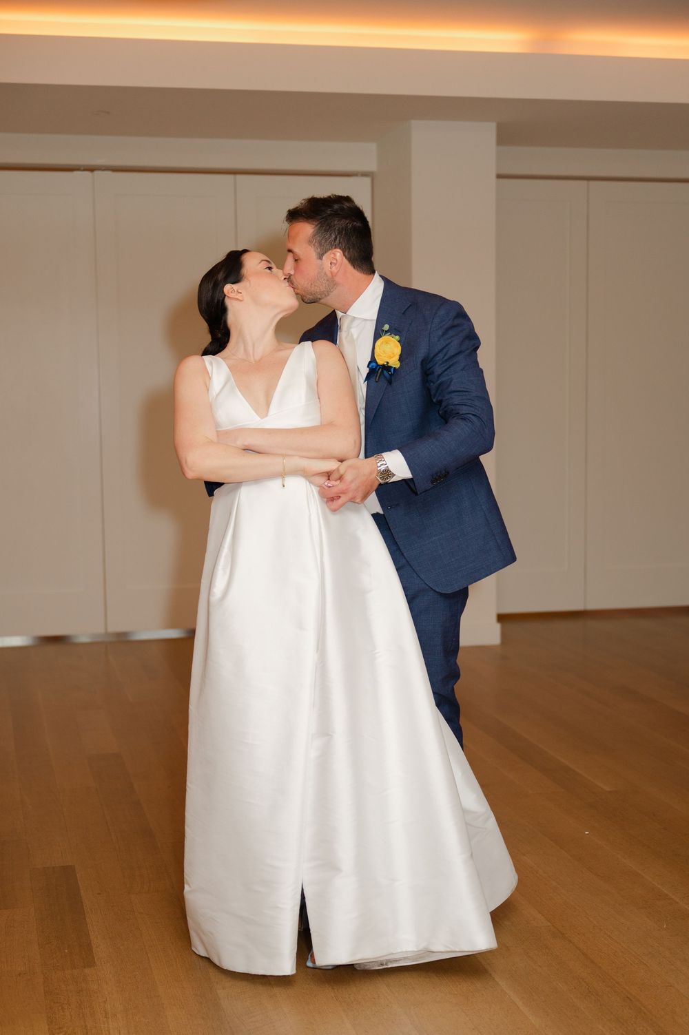 Newlywed dance together in an elegant choreographed sequence on a hardwood floor.