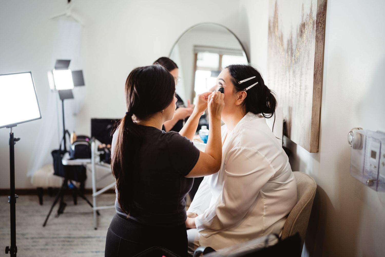 A makeup artist applies cosmetics to a client in a bright, modern salon setting.