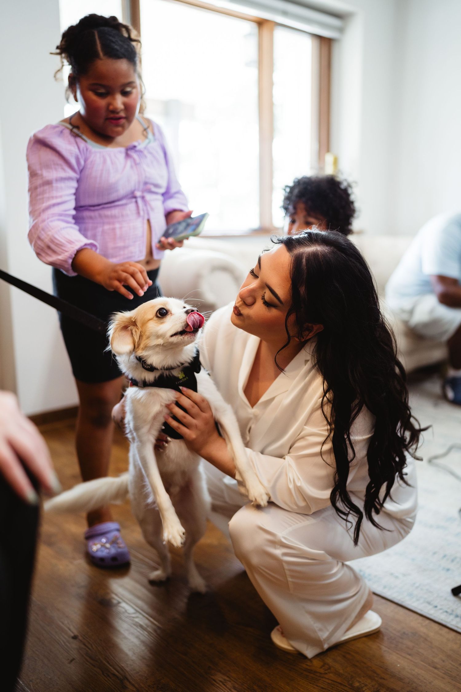 A small white dog being petted while getting ready during wedding preparations.