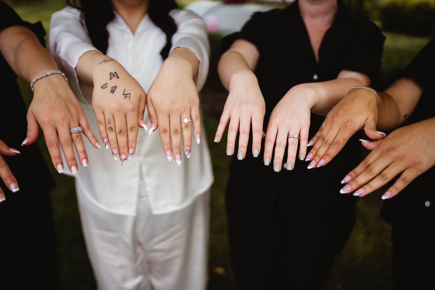 A group of people show off their wedding rings and hands in a candid photo moment.