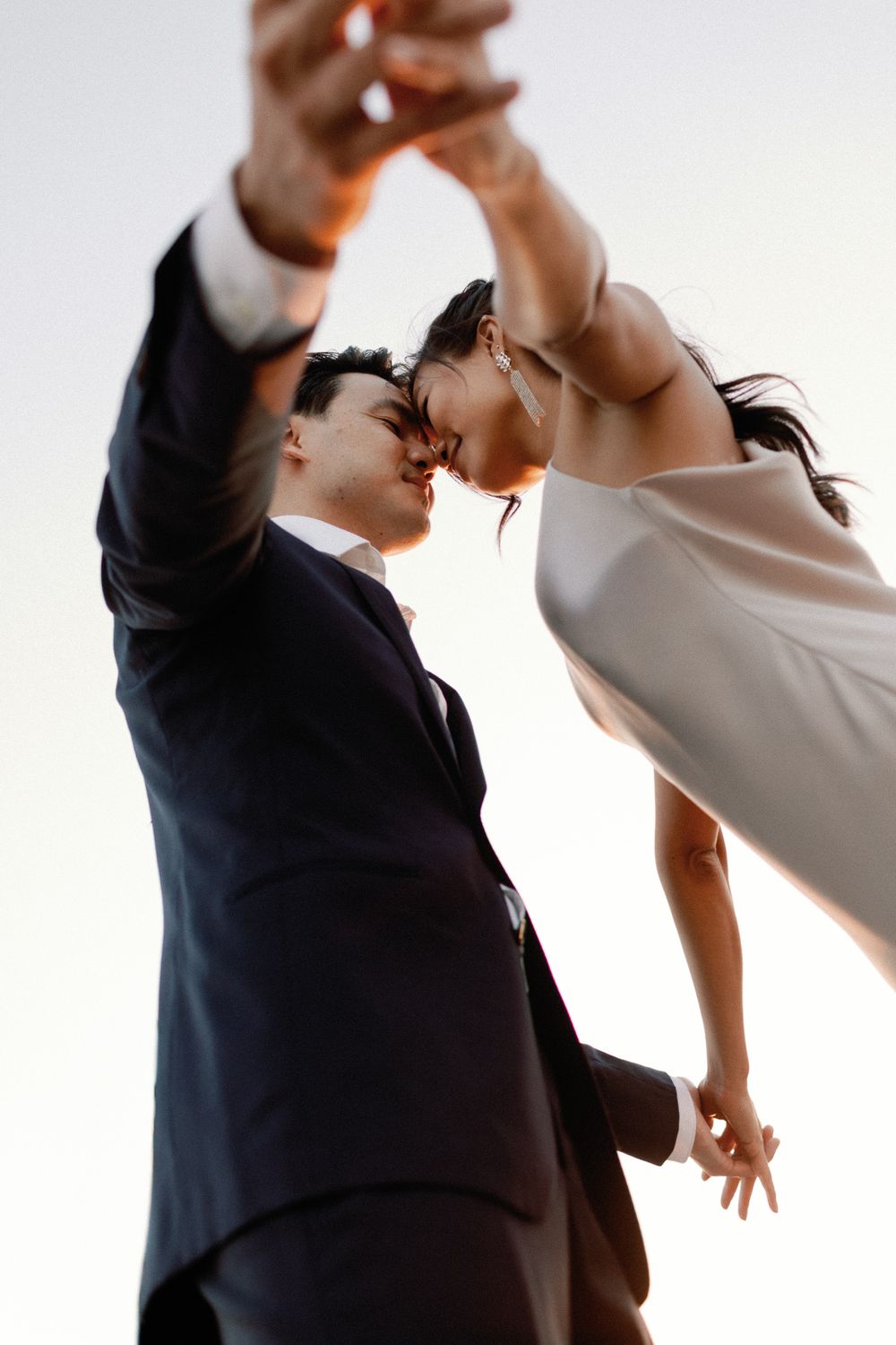 Bride and groom share a romantic kiss while dancing at golden sunset.