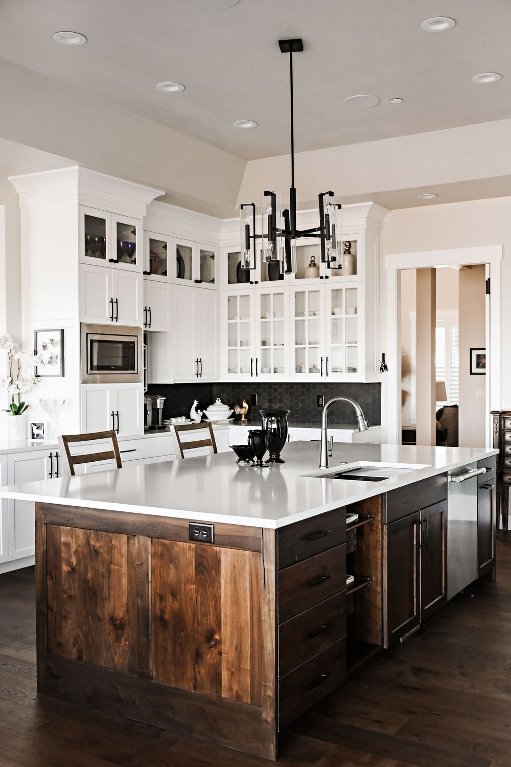 Modern farmhouse kitchen with dark wood accents, white cabinets and large center island.
