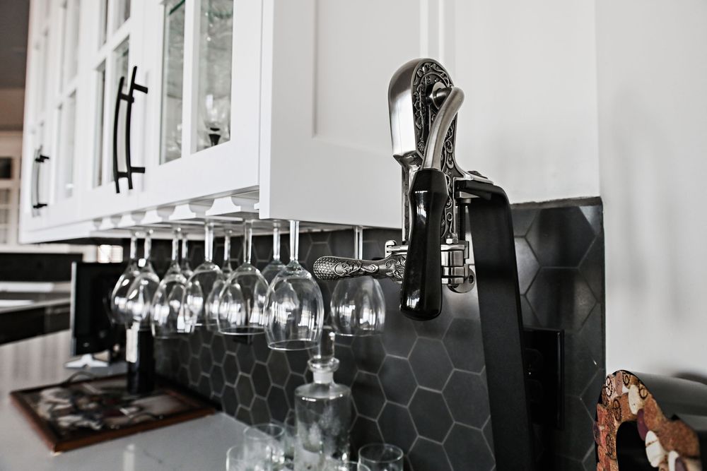 Modern bar area with wine glasses hanging upside down from overhead racks in a bright white space.