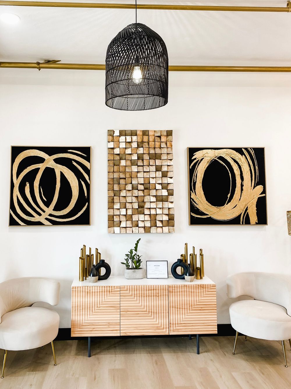 Gallery wall featuring abstract gold and black artwork with modern pendant lighting.