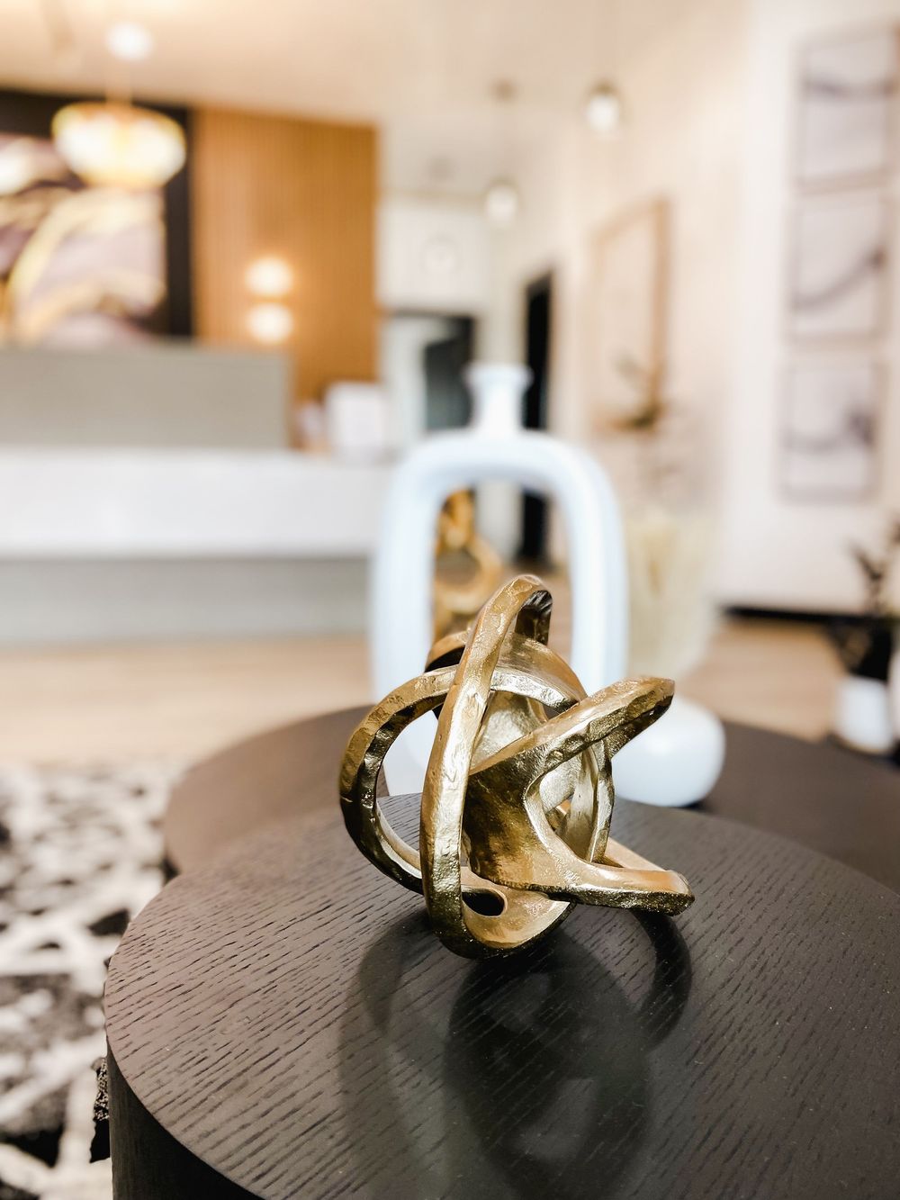 Close-up of gold sculptural decor pieces on dark wooden table surface.