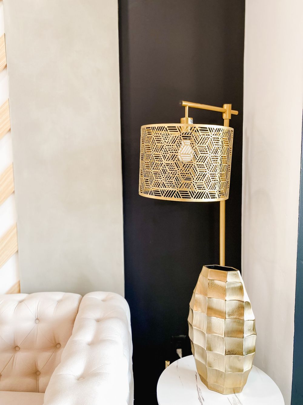 Gold geometric pendant lamp with woven pattern hanging above white tufted furniture.