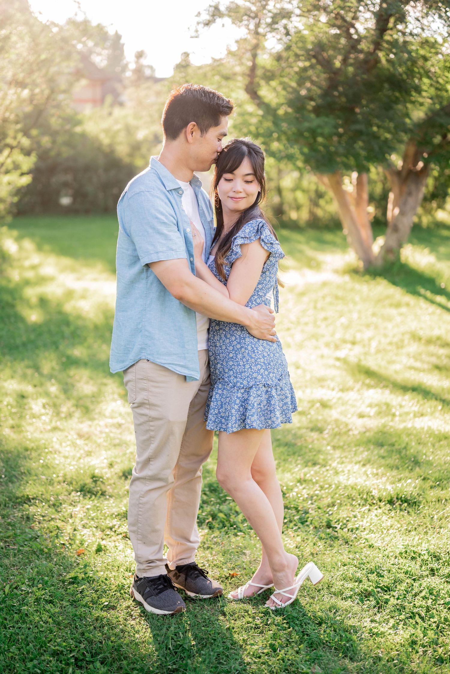 Couple in love posing playfully on a grassy hilltop during a golden sunset photoshoot.