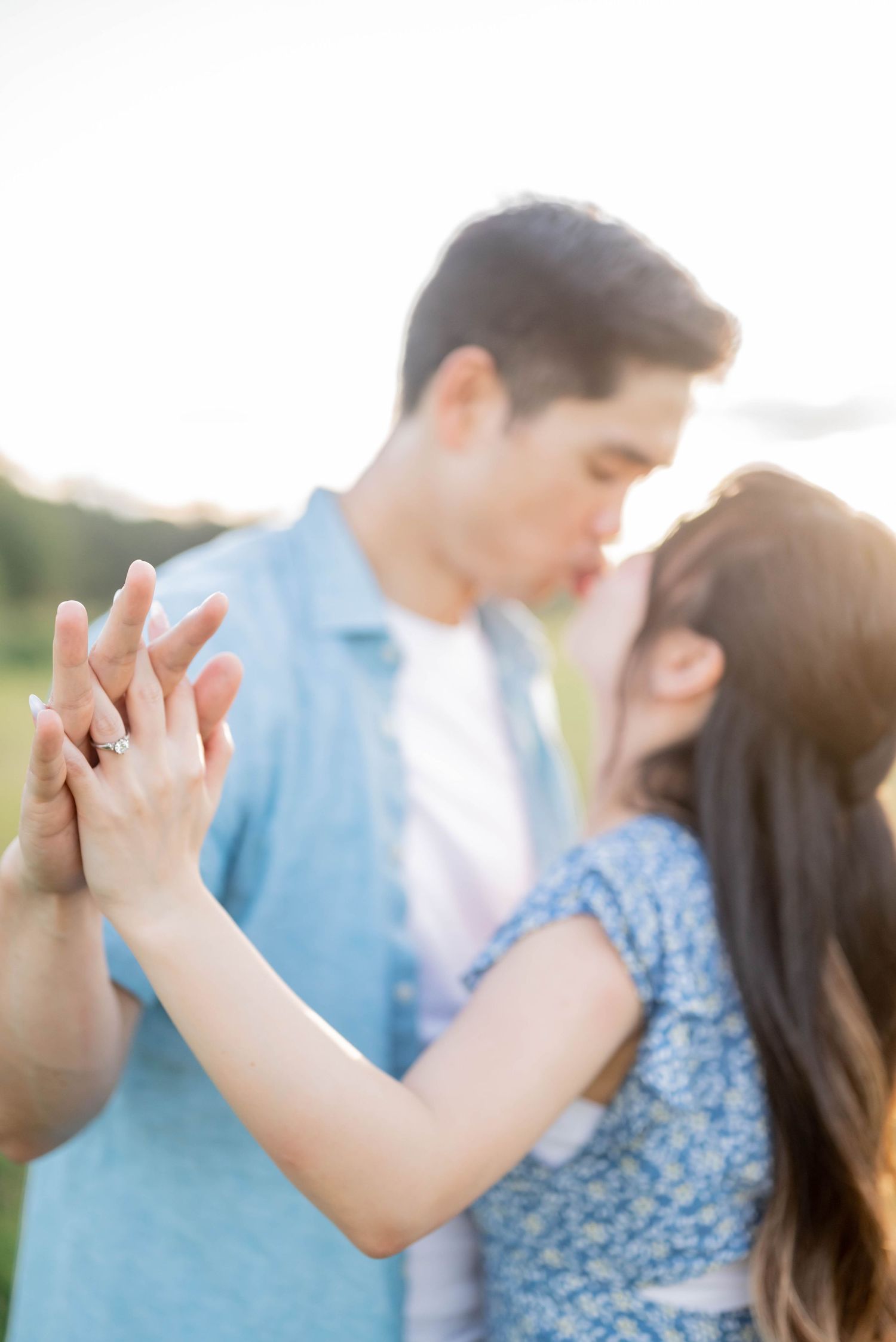 Couple in casual blue and white outfits share intimate moment during sunset photoshoot.
