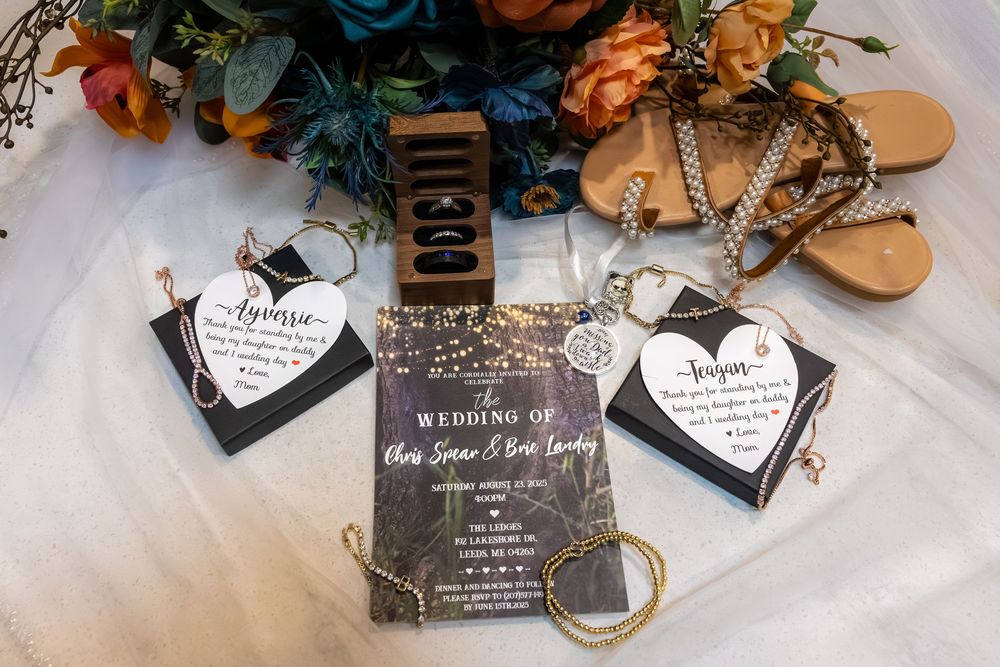 Elegant black and gold marble wedding invitation with heart shaped tags and floral decor on white tulle background.