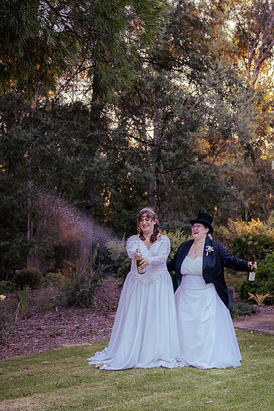 Wedding couple sitting together on grass during sunset golden hour.