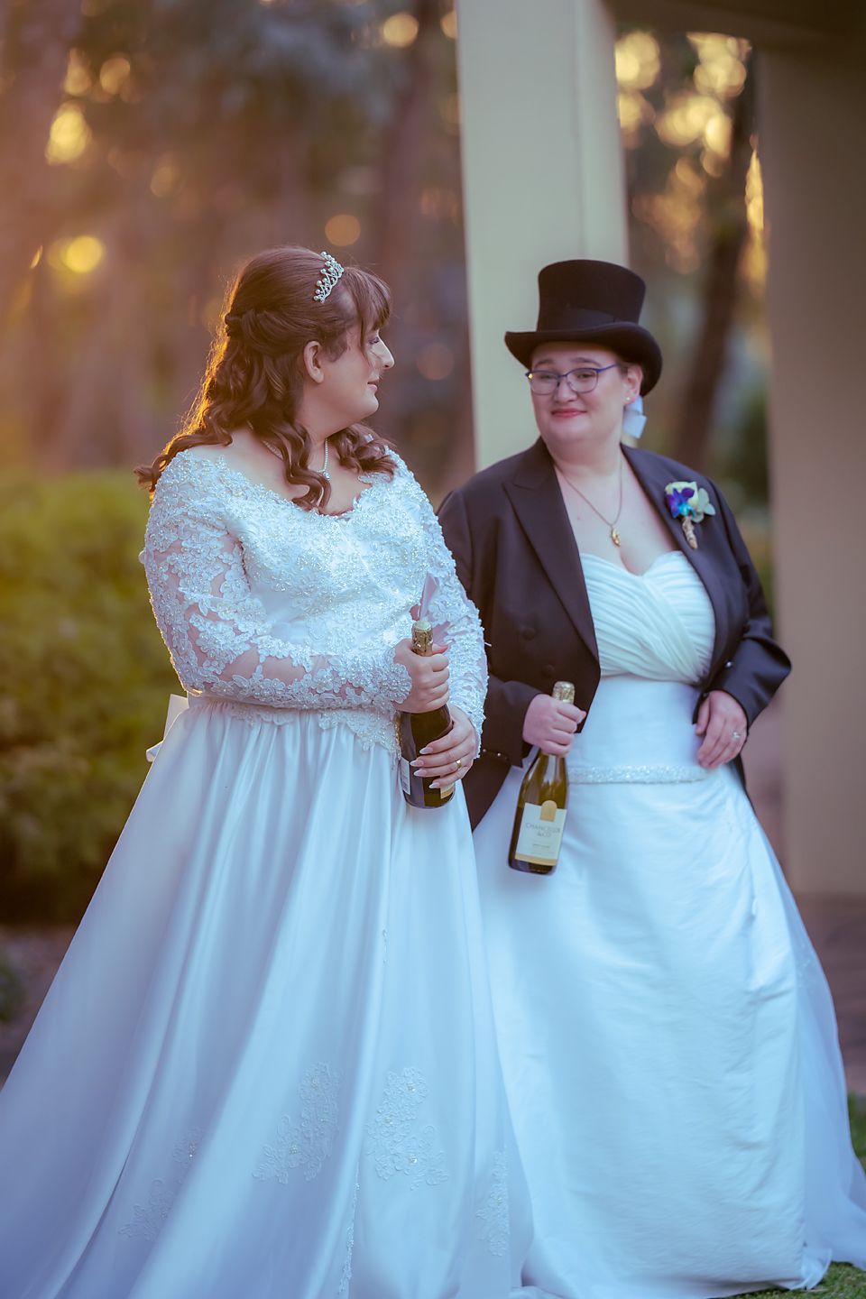 Couple in wedding attire sharing a romantic moment at sunset with soft bokeh lighting in the background.