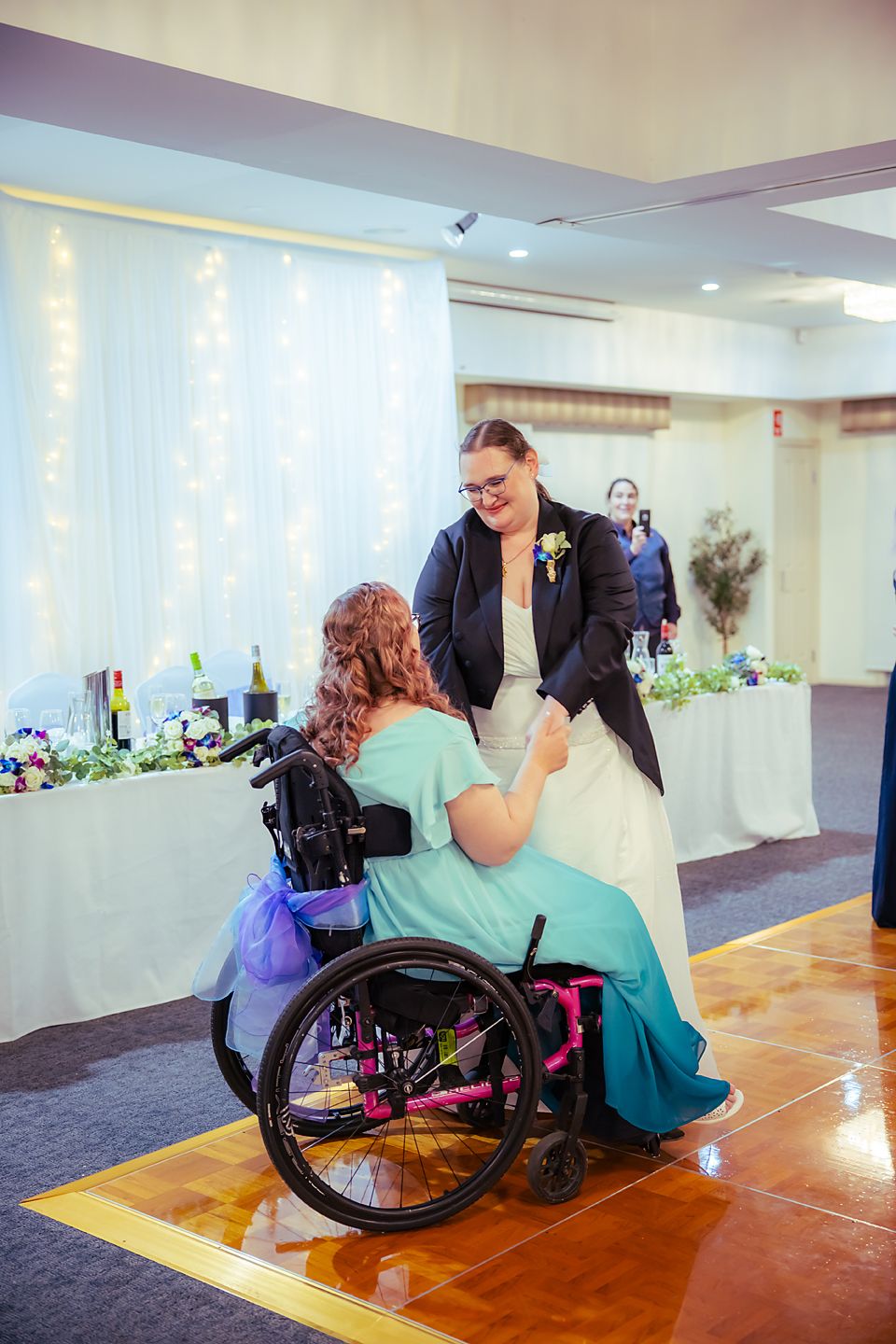 A tender moment on the dance floor as a wheelchair user in a teal dress shares a special dance with a partner.
