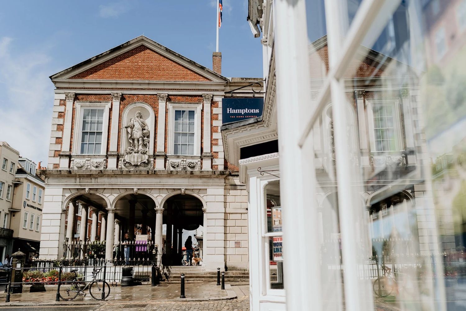 Row of classic British architecture buildings with white columns and stone facades along a street.