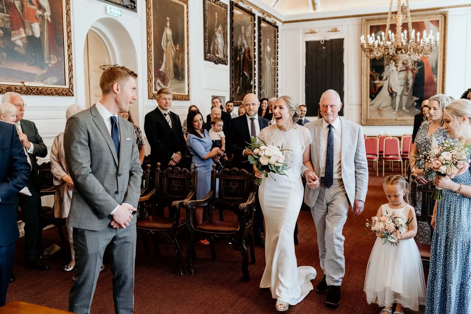 Elegant wedding reception in a historic room with chandeliers and antique paintings on display.