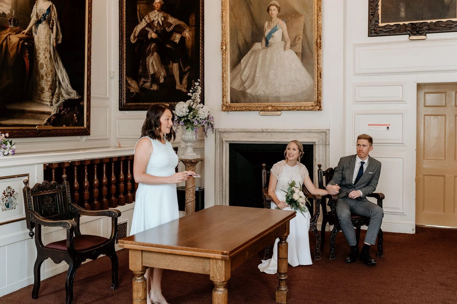 An elegant room with historic paintings serves as backdrop for a wedding ceremony.