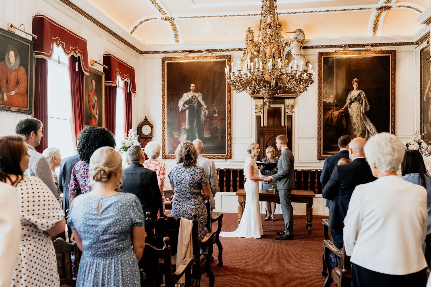 Guests gather in an elegant ballroom with crystal chandeliers and ornate decorations during a formal celebration event.