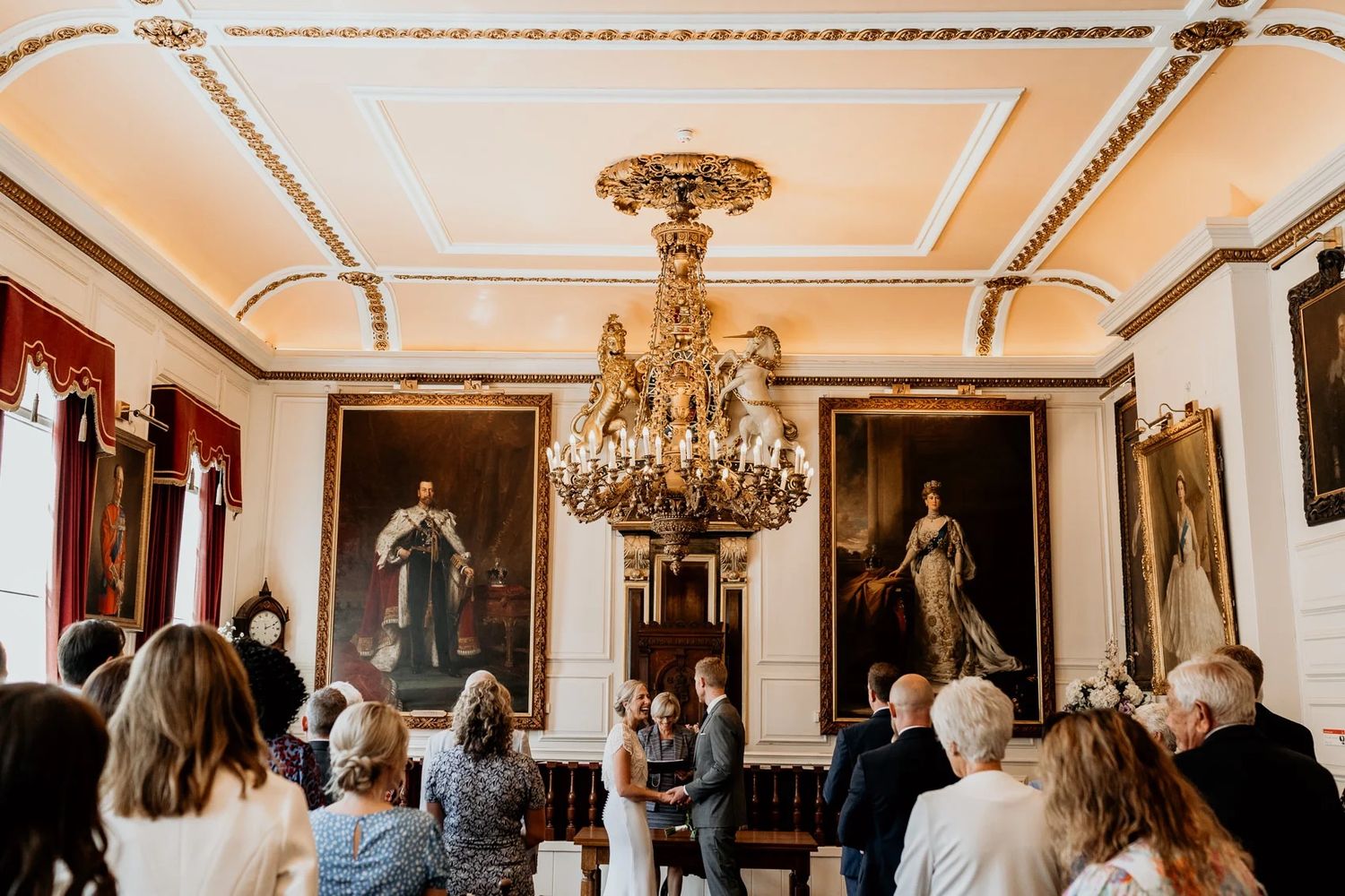 Elegant ballroom interior with ornate gold chandeliers and crown molding.