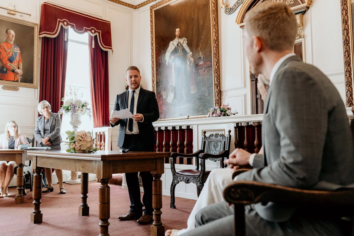 Wedding party gathered in an ornate room with vintage furniture and decorative details.