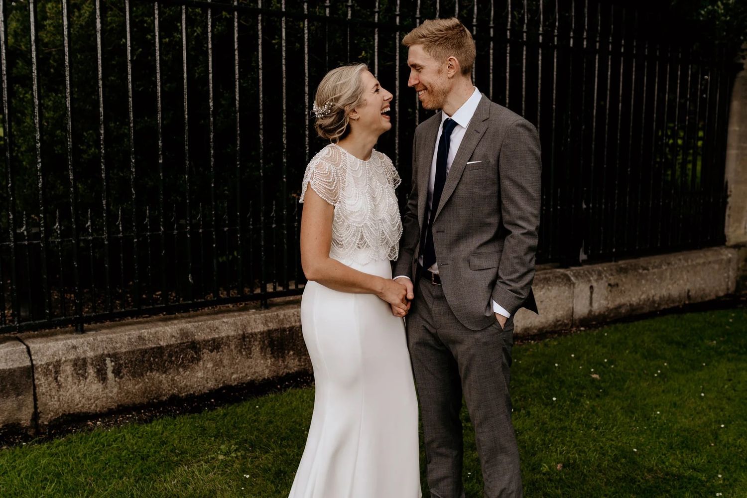 Couple sharing intimate moments in a garden setting against an iron fence.