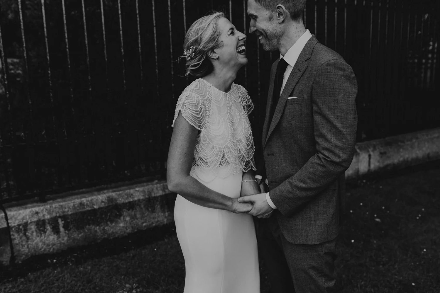Black and white portrait of a couple laughing together outdoors.
