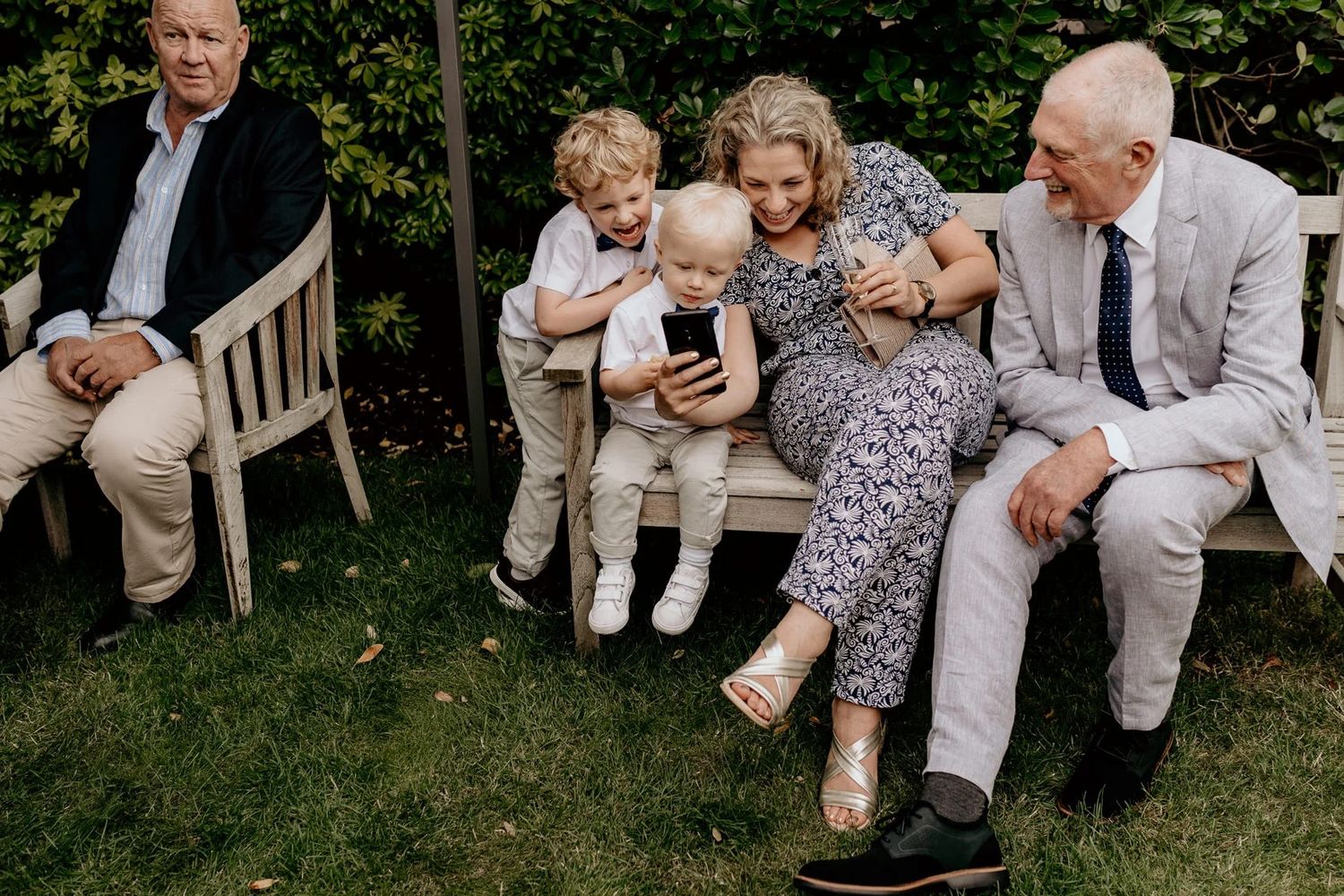 Wedding party guests relaxing on grass during an outdoor celebration.