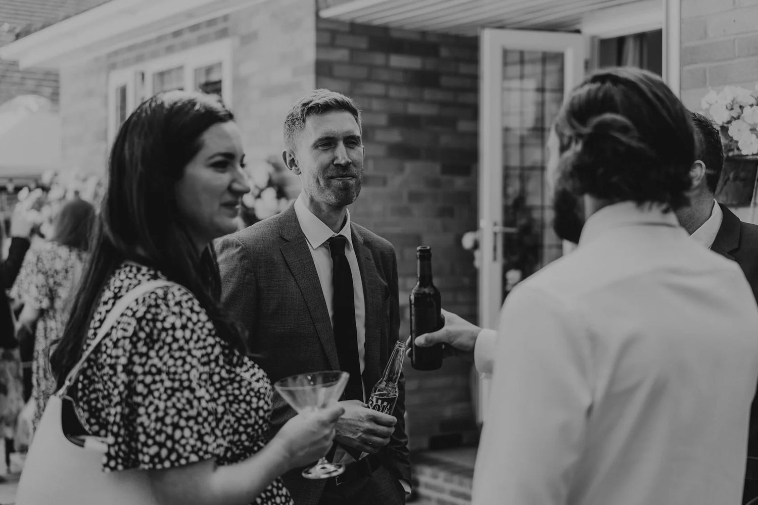 Social gathering with guests enjoying drinks and conversation on a patio.
