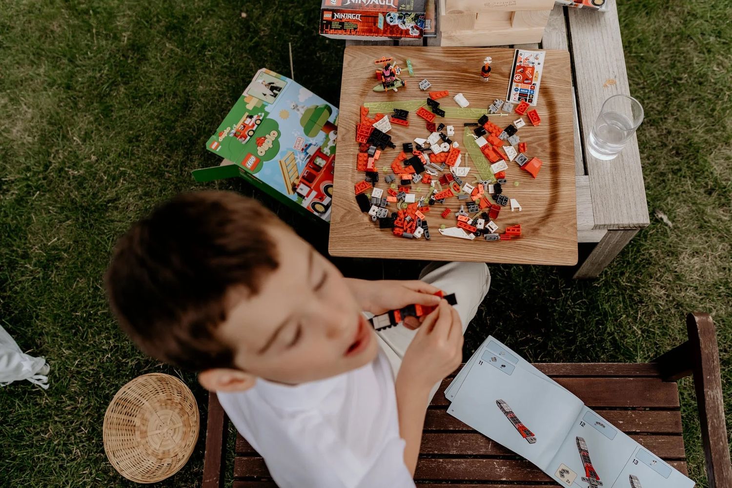 Children doing arts and crafts activities at a wooden table outdoors.