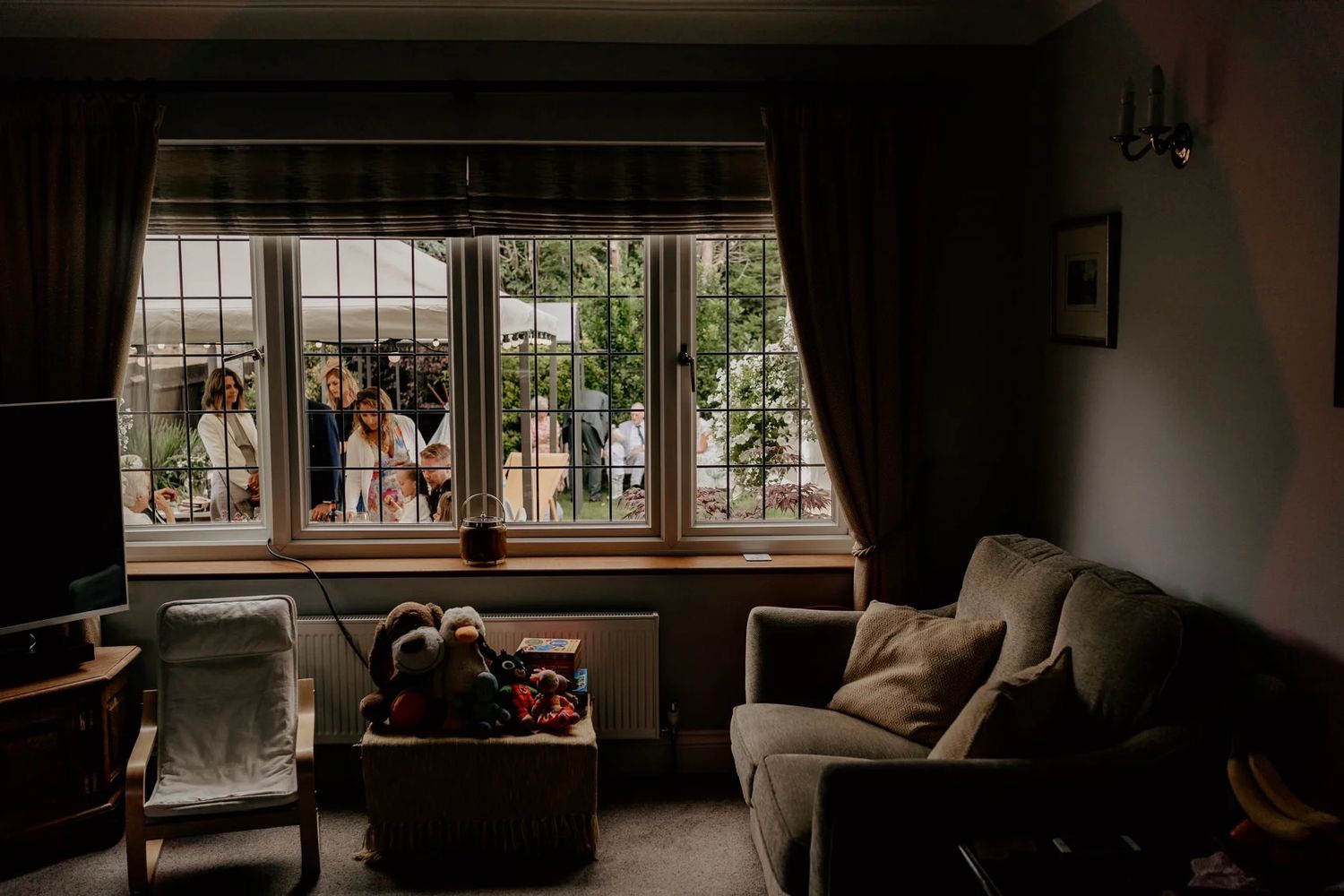 Natural light streams through large windows in a dimly lit room with interior decor.