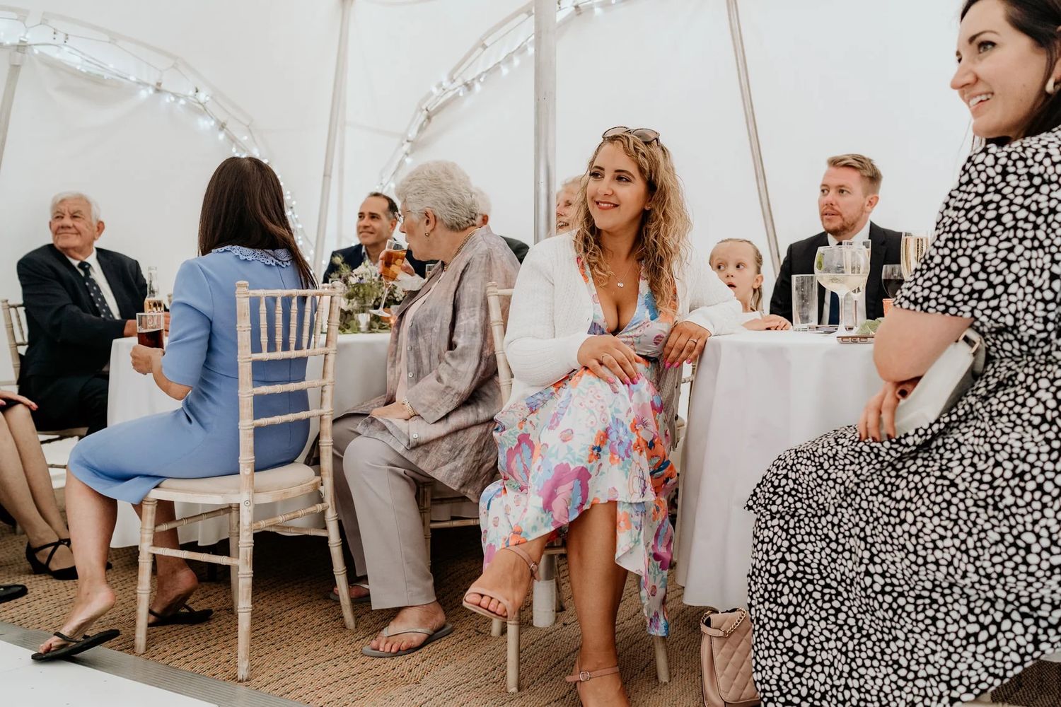Elegant white tent wedding venue setup with traditional wooden chairs arranged for a ceremony.