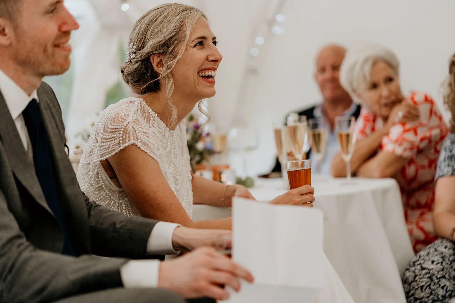 Wedding celebration candid moments showing guests laughing and socializing at tables.