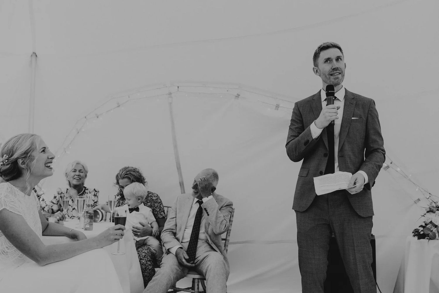 Monochrome candid shots capture joyful moments between wedding guests during an outdoor reception.