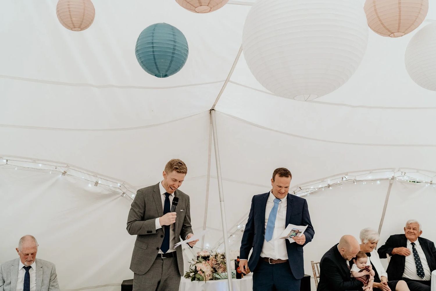 Wedding celebration inside tent with hanging pastel paper lanterns.