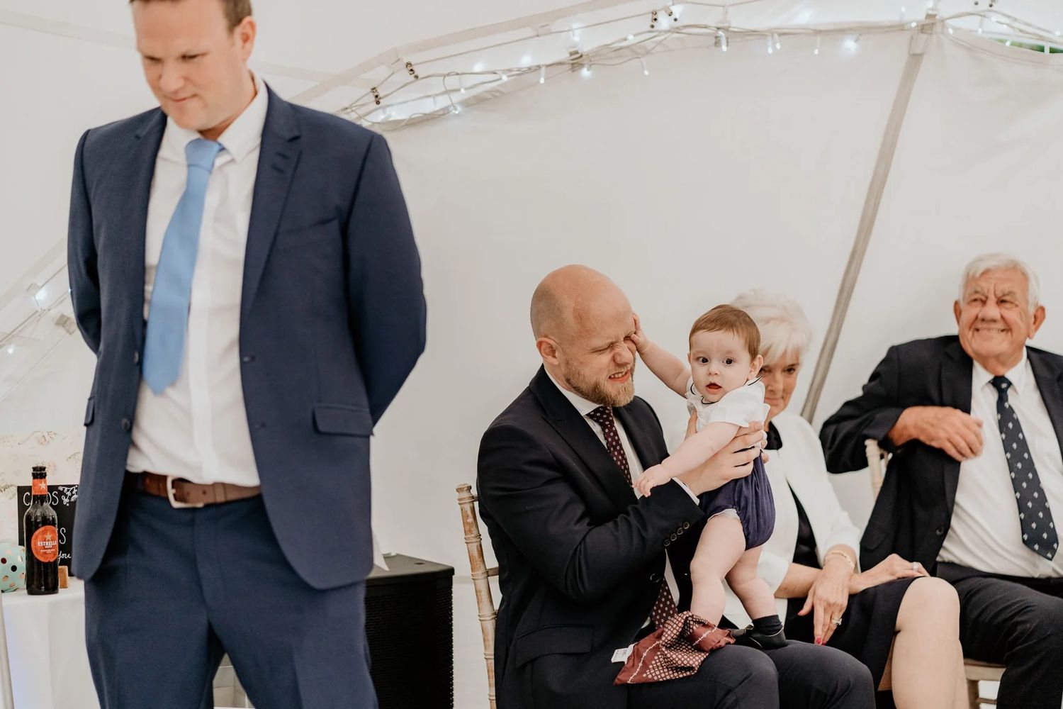 Guests mingling and conversing at an elegant wedding reception under a white tent.