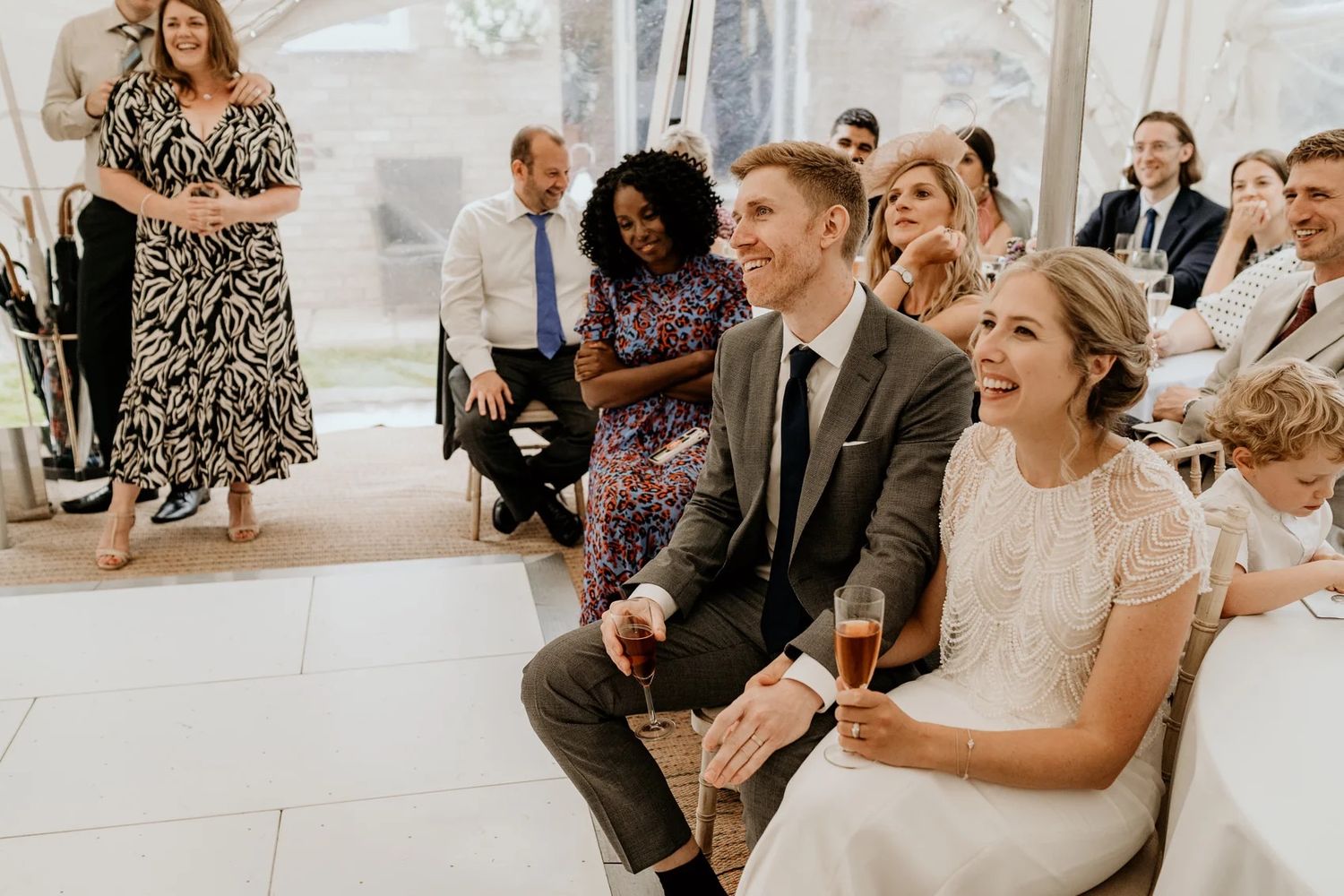 Wedding guests laughing and enjoying themselves during an indoor reception celebration.