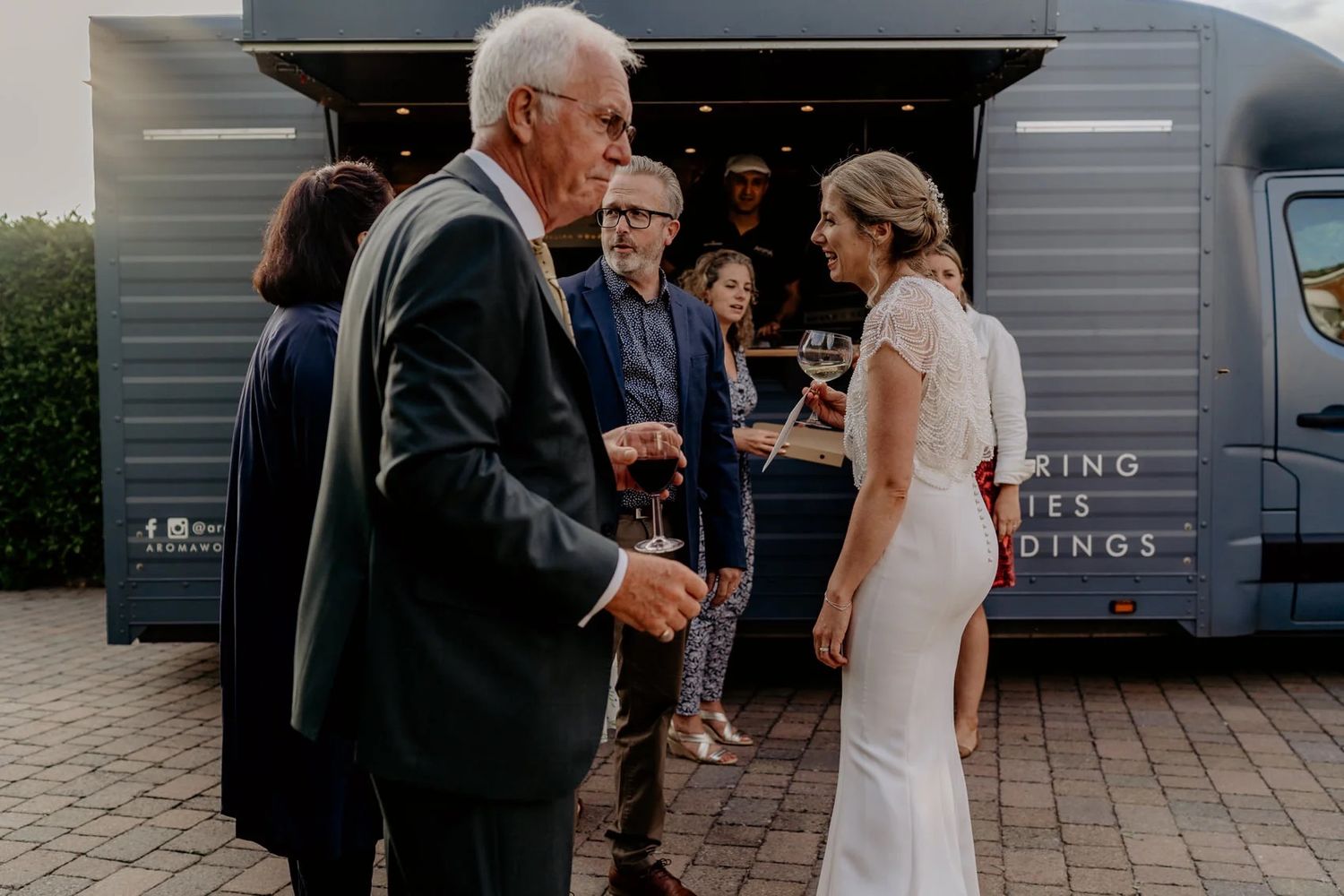 Wedding guests mingle outside a modern venue during an evening cocktail hour.