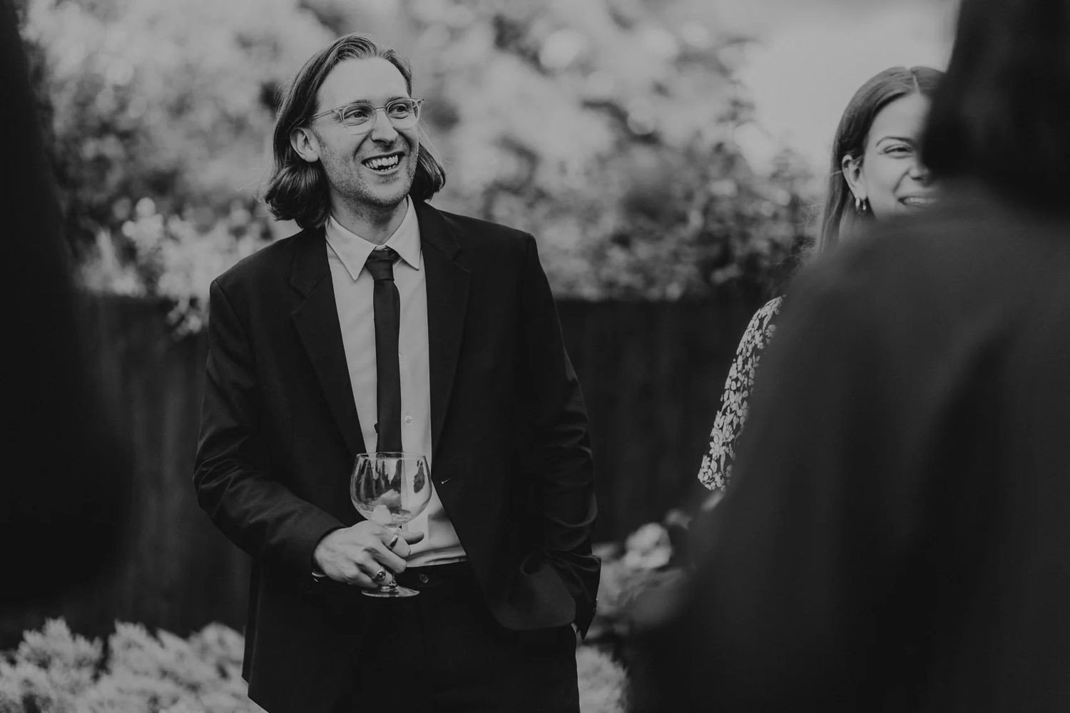 Black and white photo of joyful wedding reception moments with guests interacting.