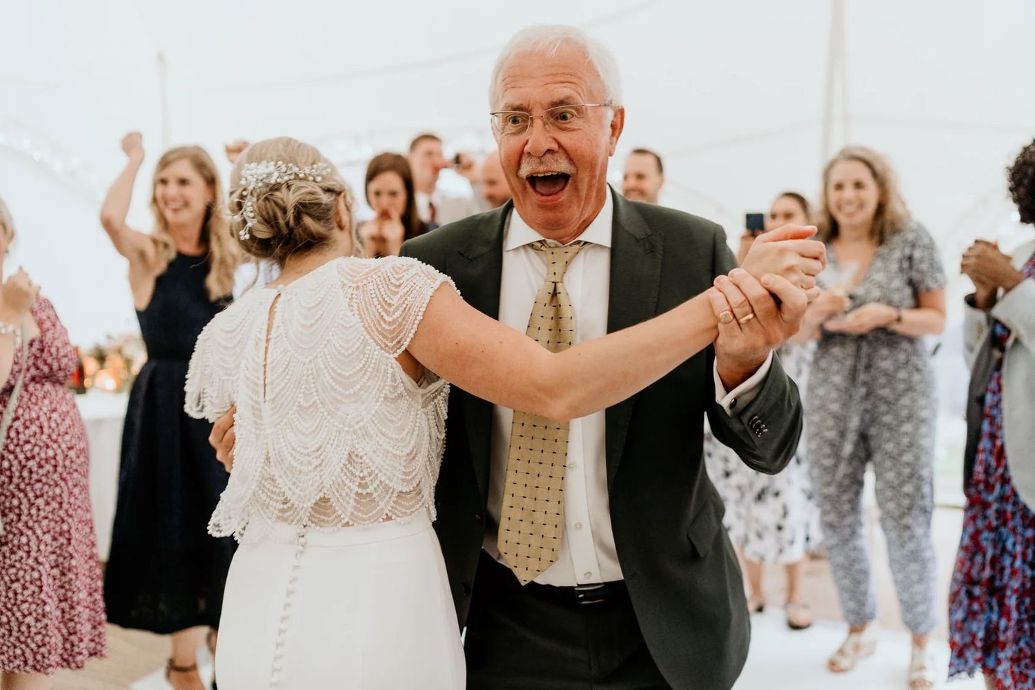 Wedding party dancing and celebrating during a lively reception gathering.