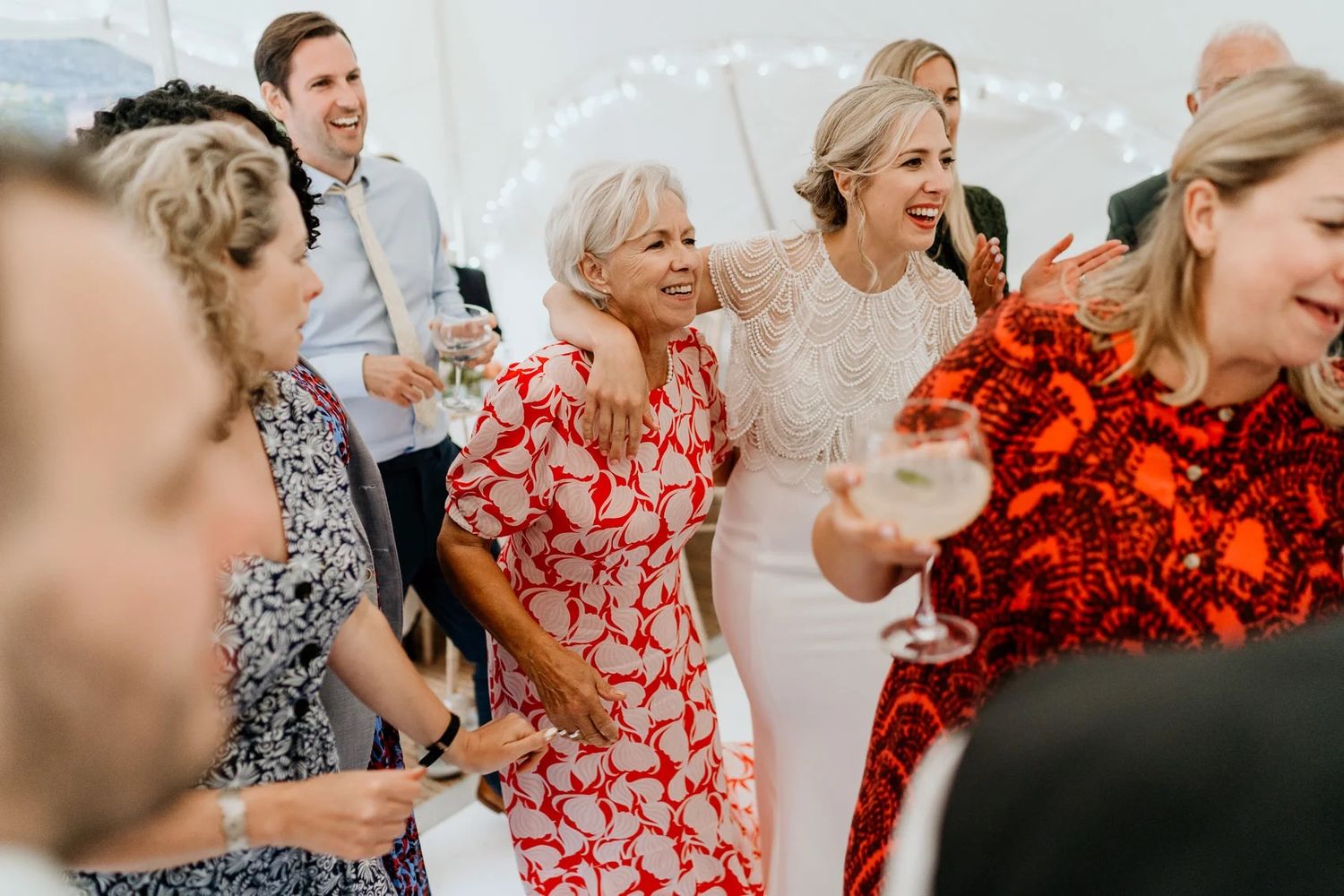 Wedding guests laughing and celebrating together in a bright indoor venue.