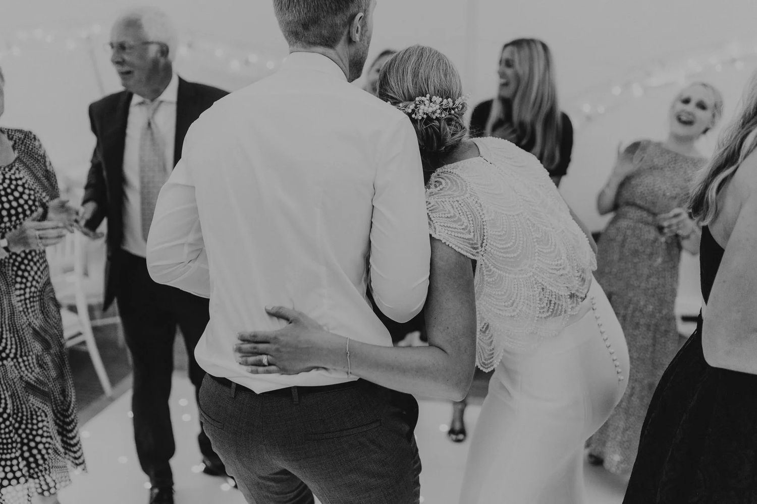Wedding guests dancing and celebrating together on a dance floor during a joyous reception.