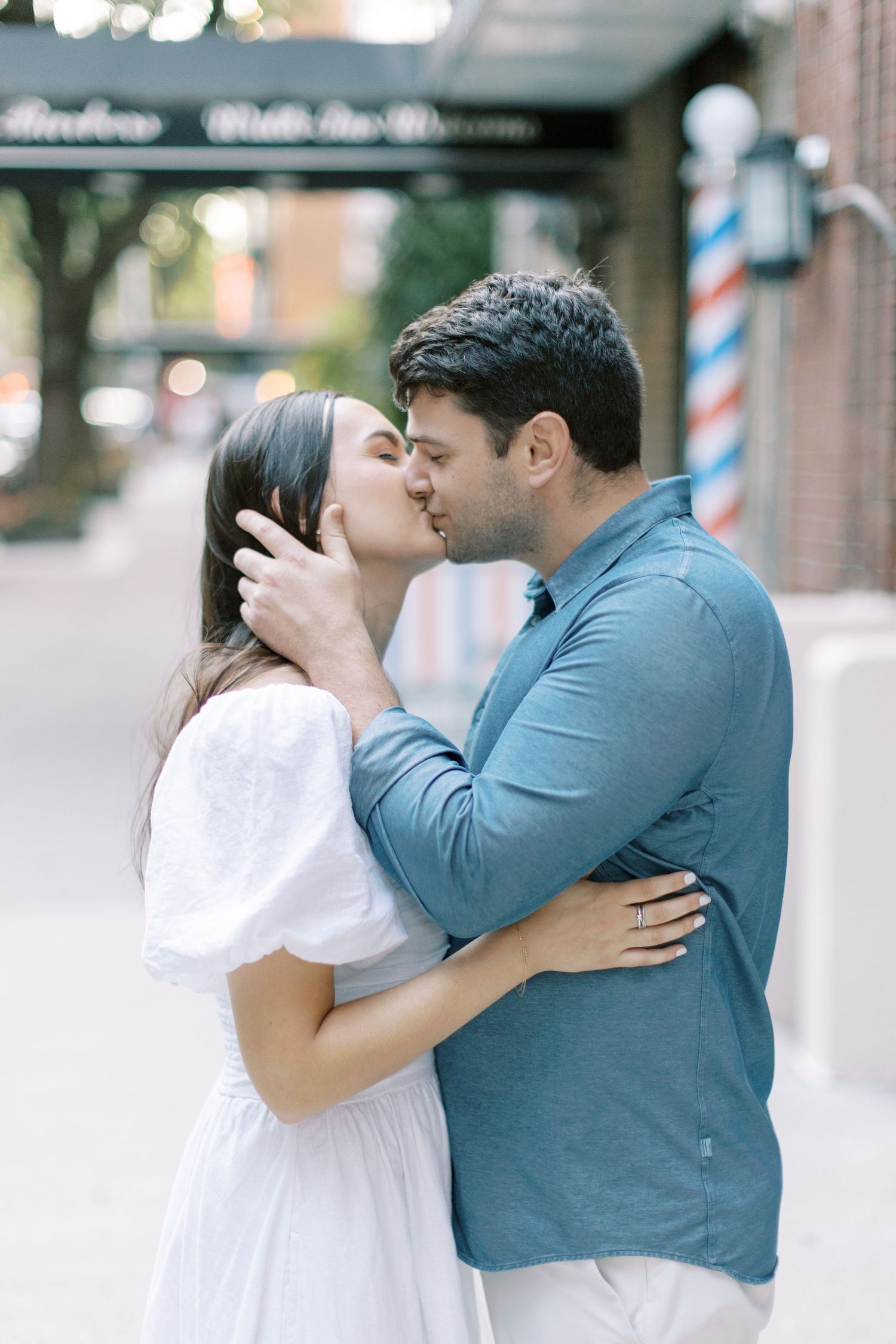 A romantic engagement photo series showing a couple in white and blue outfits sharing tender moments against an urban backdrop.